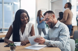Woman smiling and shaking hands with a loan officer after buying a home.